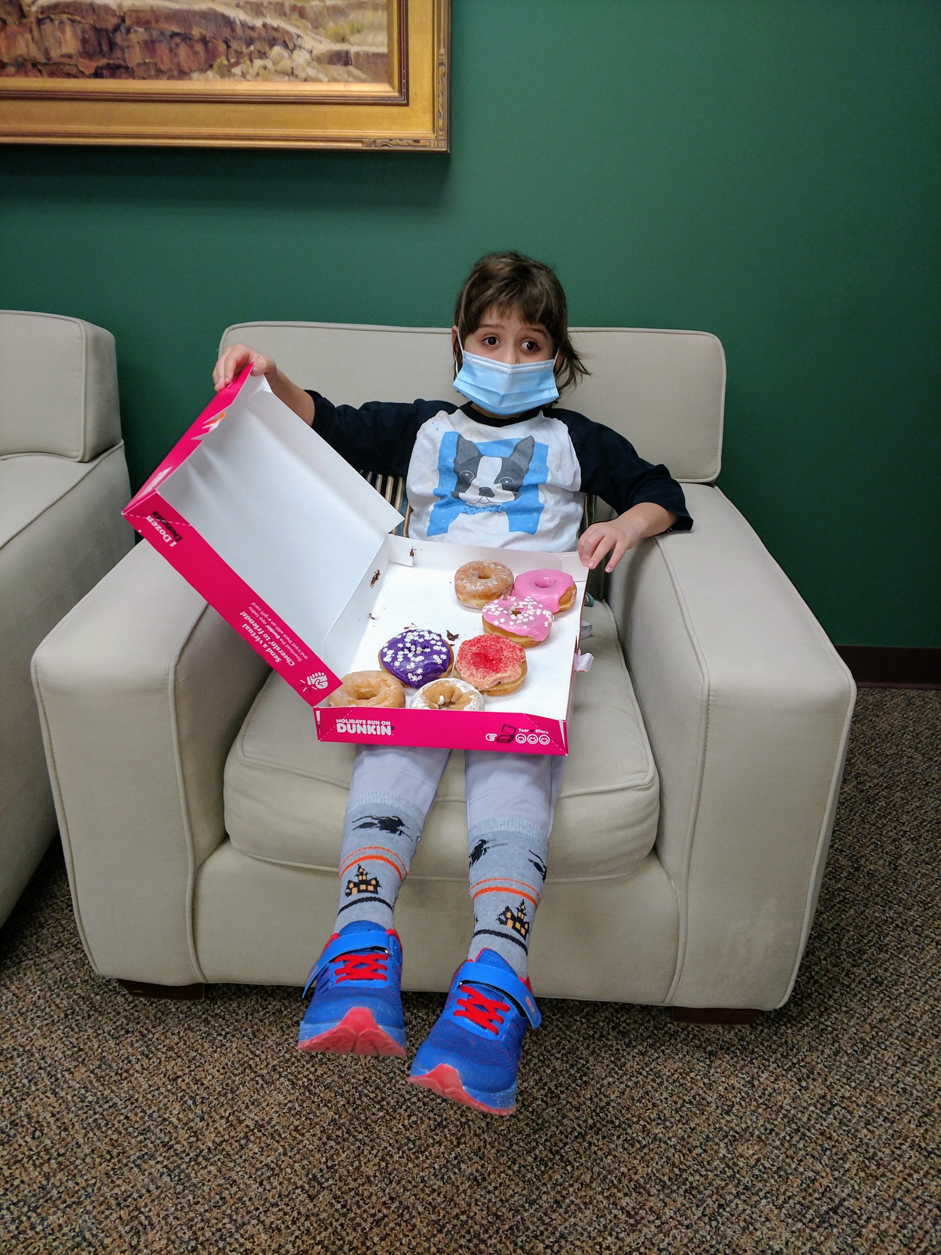 Young girl holding box of doughnuts